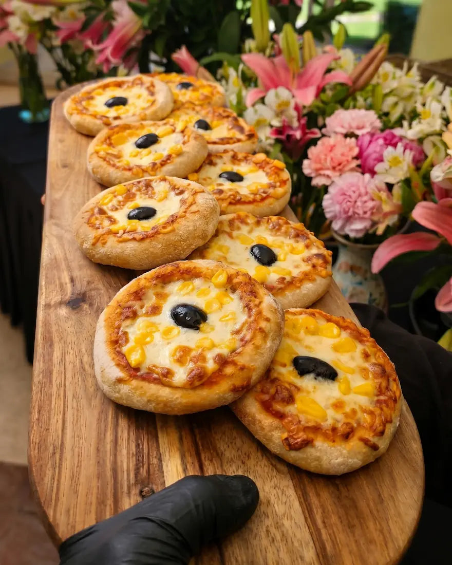 Bocado caliente de mini pizzeta italiana, banquetería premium a domicilio en Santiago.